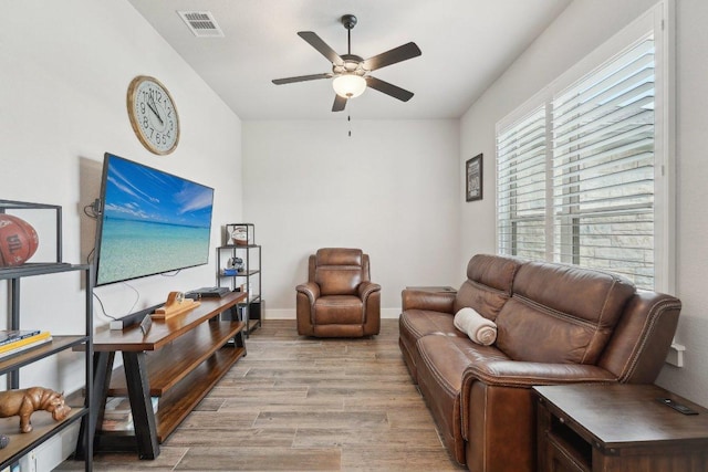 living area featuring baseboards, ceiling fan, visible vents, and wood finished floors