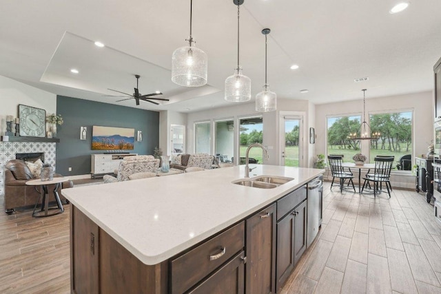 300 Red Mulberry Way, Leander, TX 78641 - kitchen with a tiled fireplace, light wood-style floors, a raised ceiling, recessed lighting, and ceiling fan