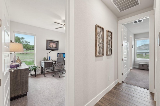 corridor featuring baseboards, wood finished floors, and visible vents
