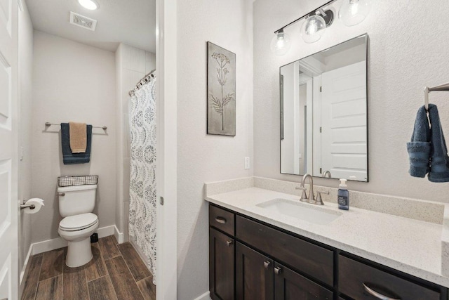 bathroom with vanity, toilet, curtained shower, wood finished floors, and visible vents