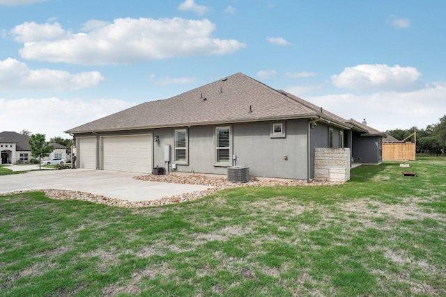 rear view of house with driveway, a lawn, central AC unit, an attached garage, and stucco siding