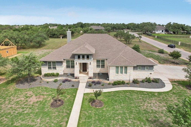 view of front of home featuring a chimney, a shingled roof, a front yard, and stone siding