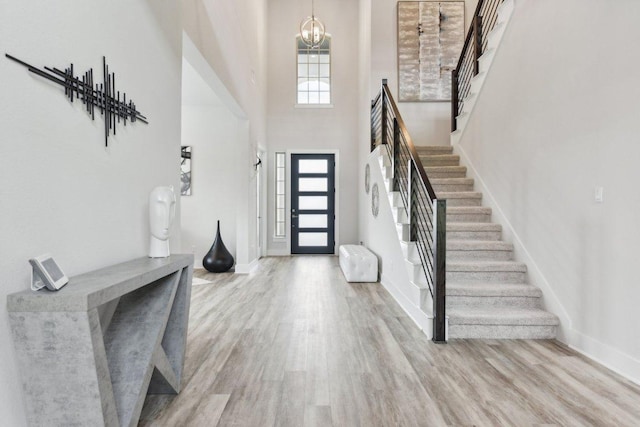 foyer entrance with stairs, a notable chandelier, and wood finished floors