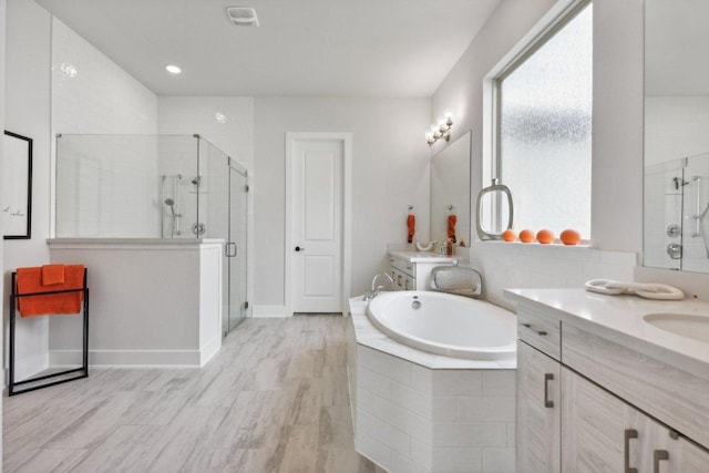 bathroom with baseboards, a bath, two vanities, a sink, and a stall shower