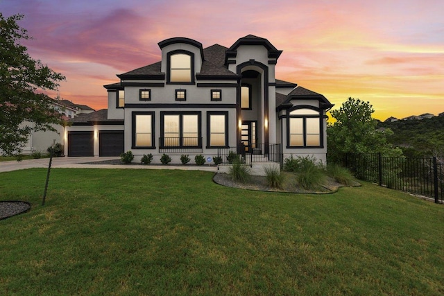 rear view of property featuring a yard, an attached garage, fence, and driveway