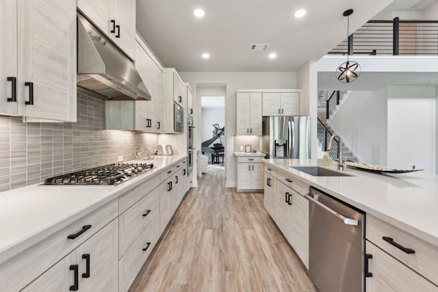 4617 Port Genova Ct, Leander, TX 78641 - kitchen featuring stainless steel appliances, under cabinet range hood, backsplash, light countertops, and light wood-type flooring
