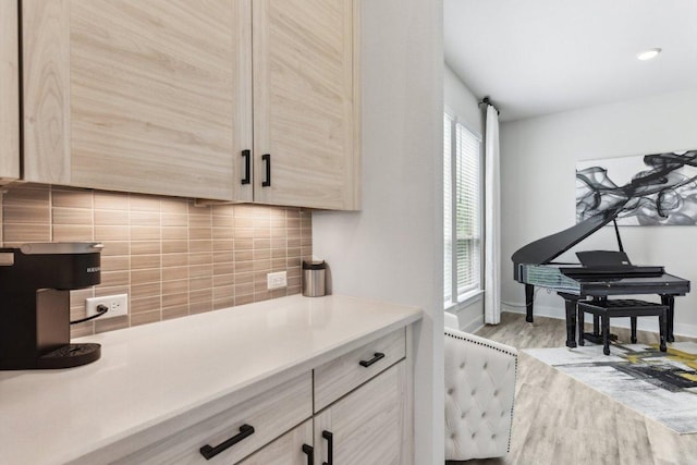 kitchen with wood finished floors, light brown cabinets, baseboards, light countertops, and tasteful backsplash