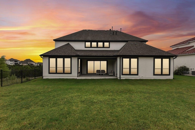 rear view of house featuring a patio area, roof with shingles, fence, and a yard