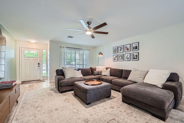 living room with visible vents, baseboards, ceiling fan, and wood finished floors