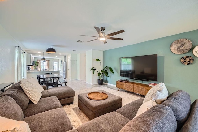 living area with ceiling fan, visible vents, and baseboards
