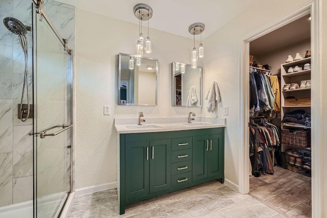 bathroom with a walk in closet, a shower stall, and a sink