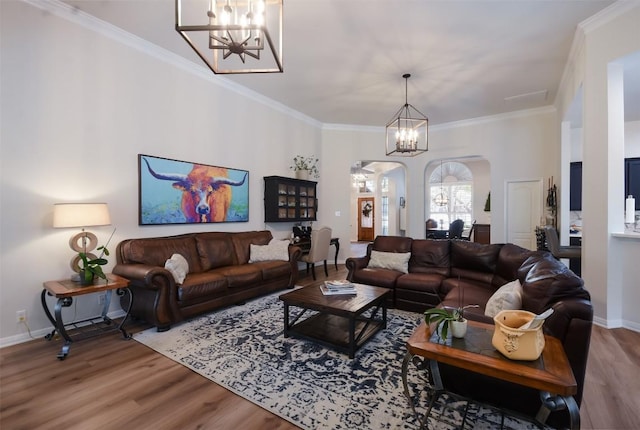 1312 Becca Teal Pl, Round Rock, TX 78681 - living room featuring arched walkways, a chandelier, wood finished floors, baseboards, and ornamental molding