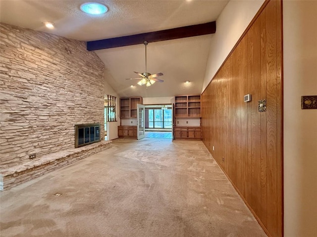 unfurnished living room with a ceiling fan, a textured ceiling, light colored carpet, a large fireplace, and lofted ceiling with beams