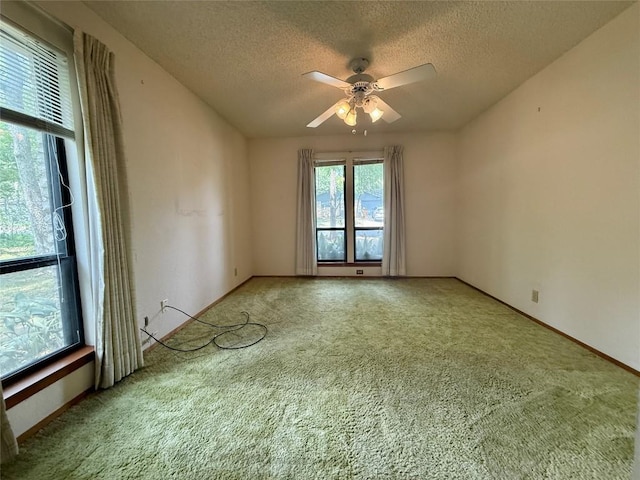 carpeted spare room featuring baseboards, a textured ceiling, and ceiling fan