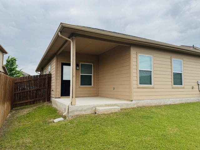 back of property with a lawn, a patio area, and fence