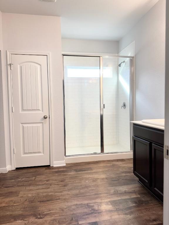full bathroom with visible vents, a shower stall, wood finished floors, and vanity