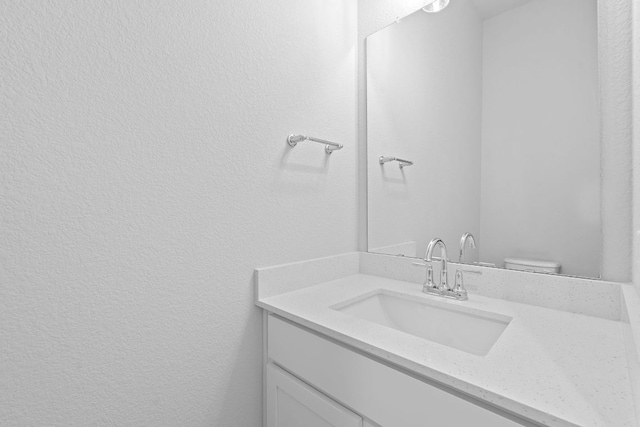 bathroom with a textured wall and vanity