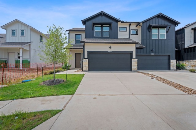 view of front of home featuring board and batten siding, driveway, a front yard, an attached garage, and stone siding