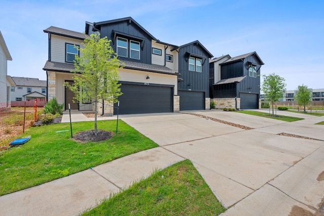 view of front facade featuring an attached garage, a front lawn, stone siding, board and batten siding, and driveway