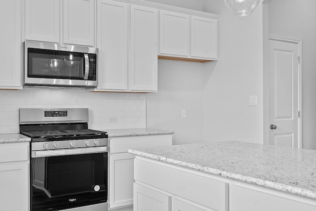 kitchen featuring appliances with stainless steel finishes, light stone counters, backsplash, and white cabinetry