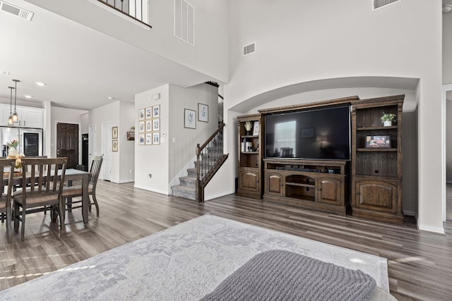 living room with stairway, baseboards, wood finished floors, and visible vents