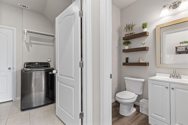 bathroom featuring visible vents, vanity, toilet, baseboards, and washer / clothes dryer
