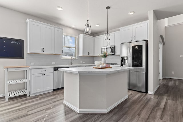 kitchen featuring white cabinetry, appliances with stainless steel finishes, wood finished floors, and tasteful backsplash