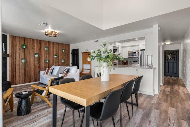 dining area featuring wooden walls, visible vents, and light wood-style floors