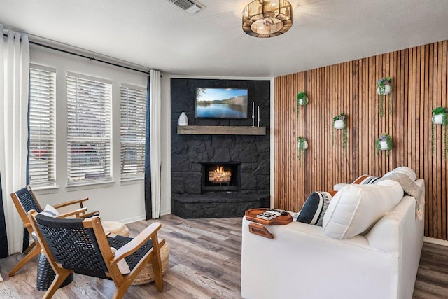 living room with a wealth of natural light, a fireplace, wood finished floors, and visible vents
