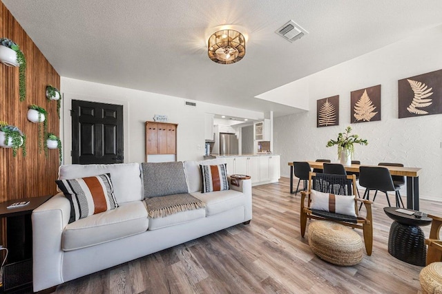 living area featuring baseboards, light wood-type flooring, and visible vents