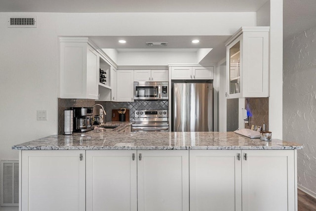 kitchen with a sink, appliances with stainless steel finishes, light stone countertops, and visible vents