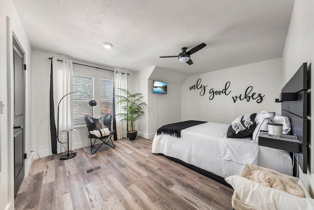 bedroom featuring visible vents, baseboards, a textured ceiling, and wood finished floors