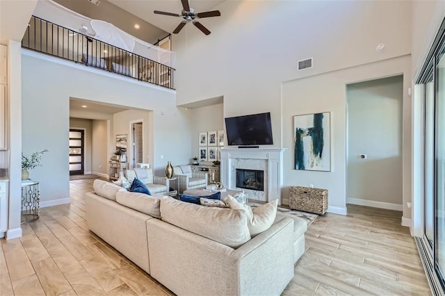 6914 Halesboro Dr, Austin, TX 78736 - living area with ceiling fan, a fireplace, light wood-type flooring, baseboards, and a high ceiling