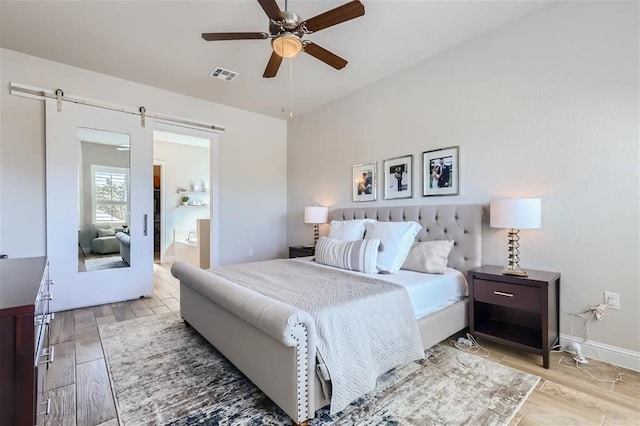 6914 Halesboro Dr, Austin, TX 78736 - bedroom featuring connected bathroom, a barn door, light wood finished floors, baseboards, and visible vents