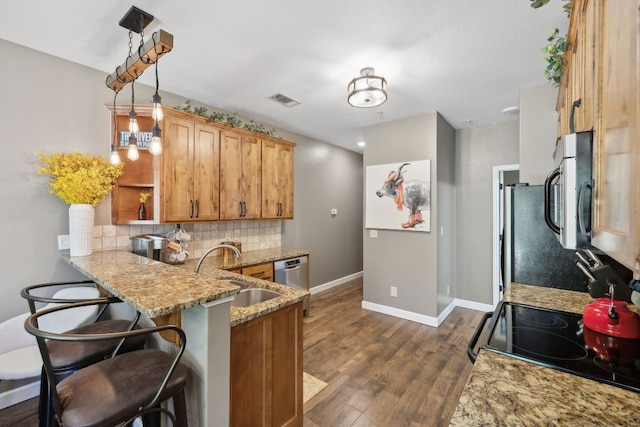 kitchen featuring dark wood-style floors, light stone counters, a sink, backsplash, and stainless steel appliances