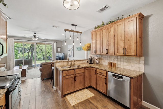 kitchen featuring visible vents, decorative backsplash, a peninsula, a sink, and appliances with stainless steel finishes