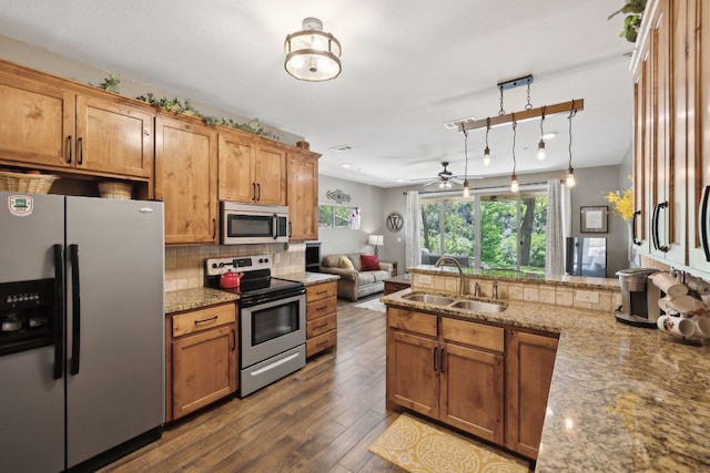 kitchen featuring ceiling fan, decorative backsplash, appliances with stainless steel finishes, a sink, and a peninsula