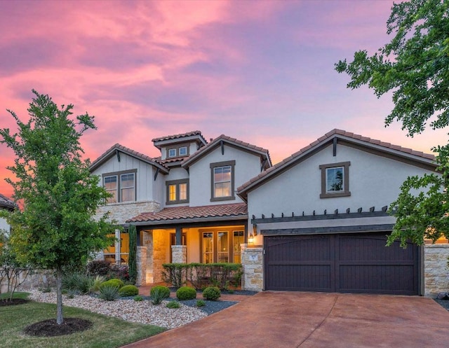 mediterranean / spanish house with a porch, a tiled roof, driveway, stone siding, and stucco siding