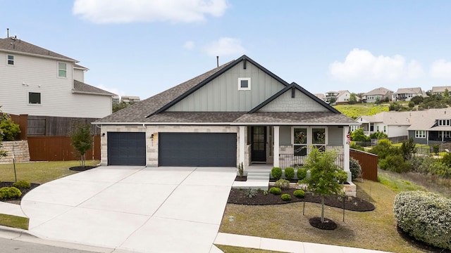 view of front of property featuring board and batten siding, covered porch, driveway, roof with shingles, and a garage