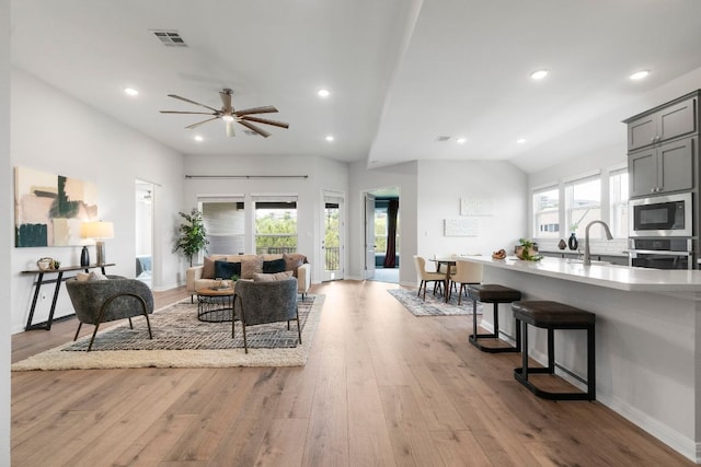 living area with ceiling fan, visible vents, light wood finished floors, lofted ceiling, and recessed lighting