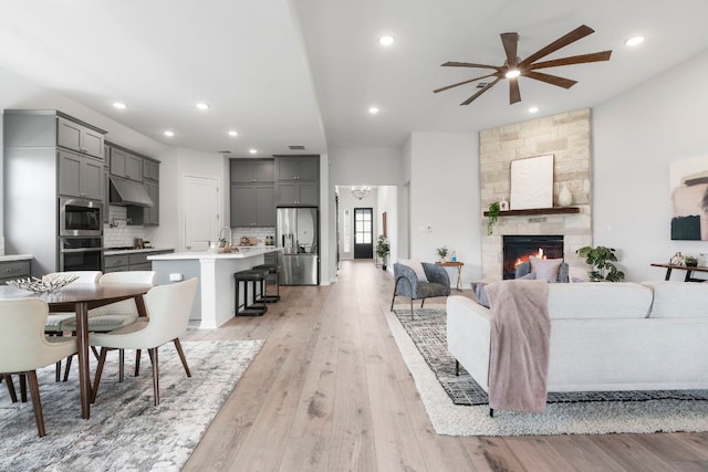 living room featuring light wood-style floors, a ceiling fan, recessed lighting, and a fireplace