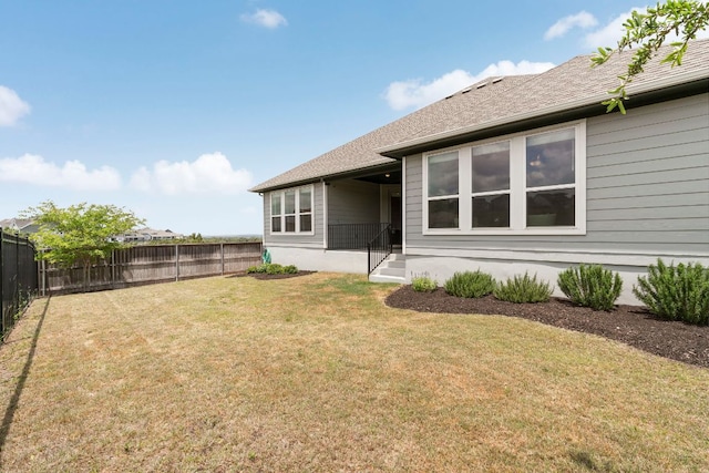 rear view of property featuring a lawn and a fenced backyard