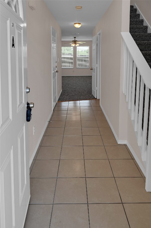 hallway with light tile patterned floors and baseboards