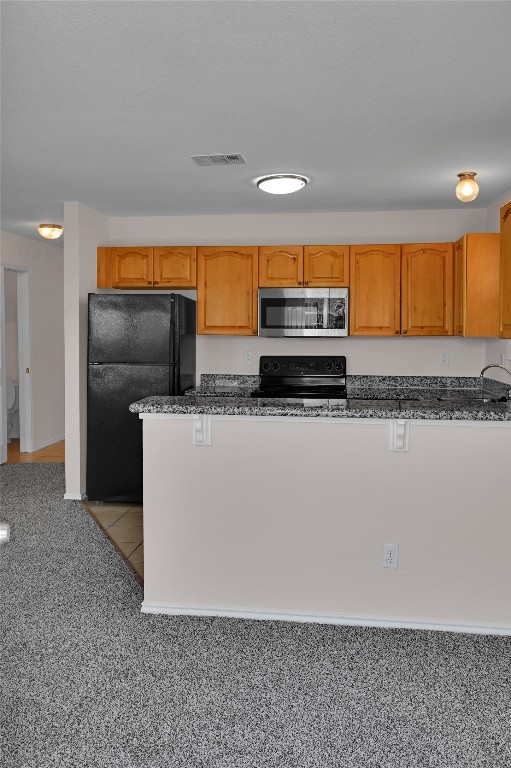 kitchen with visible vents, dark stone counters, and black appliances