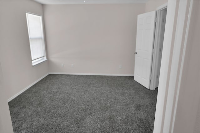 empty room with baseboards and dark colored carpet