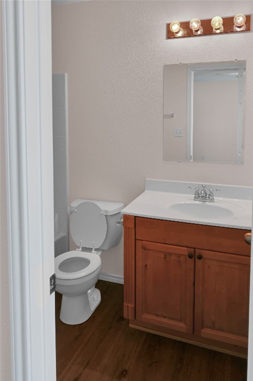 full bathroom featuring vanity, wood finished floors, toilet, a washtub, and baseboards