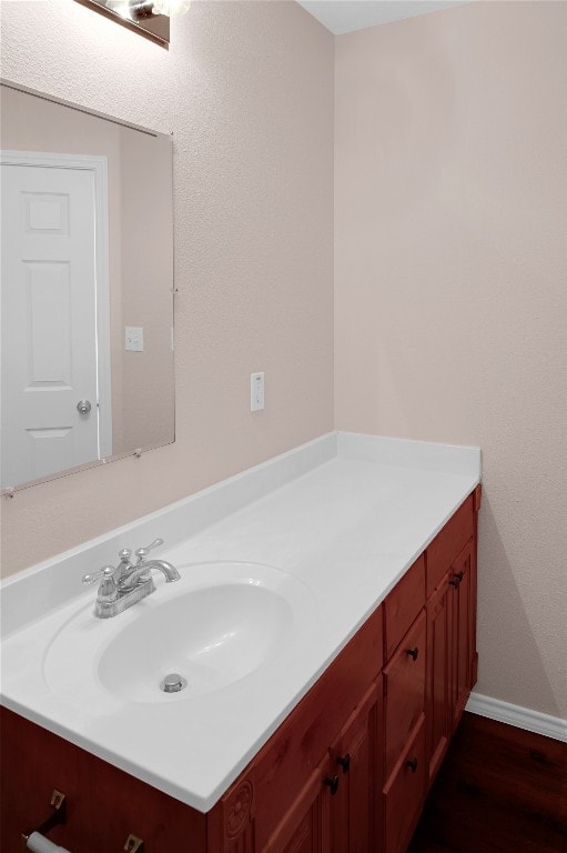 bathroom featuring vanity, baseboards, and wood finished floors