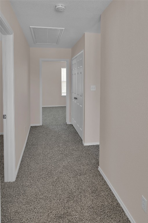 corridor featuring carpet flooring, baseboards, and attic access