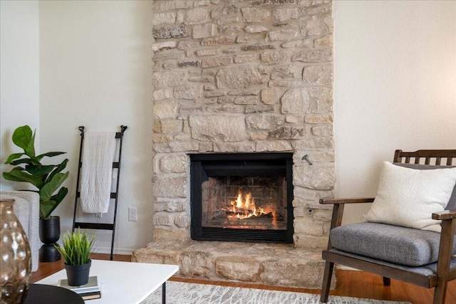 interior space with a stone fireplace, baseboards, and wood finished floors