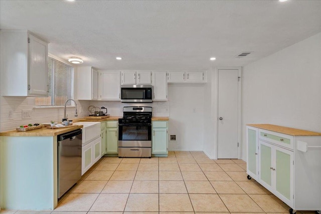 kitchen featuring visible vents, decorative backsplash, light countertops, white cabinets, and appliances with stainless steel finishes